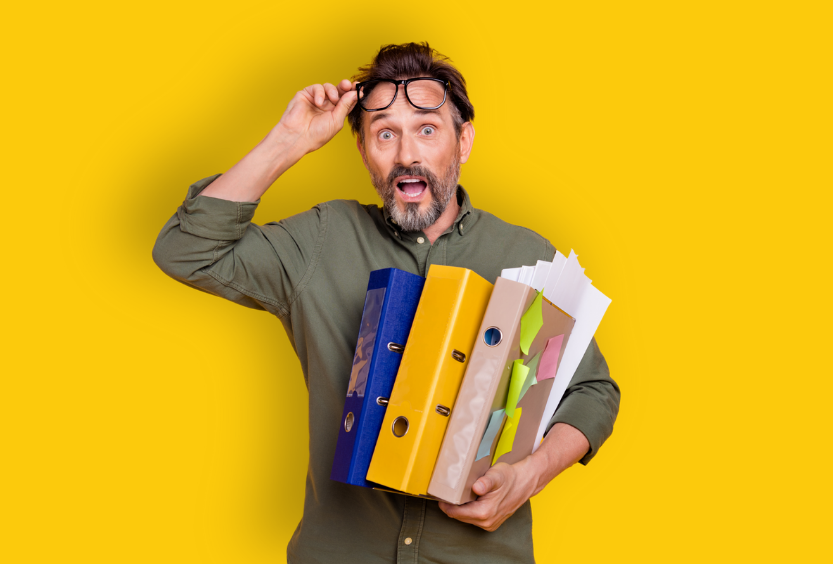 Homme stressé tenant plein de classeurs et documents